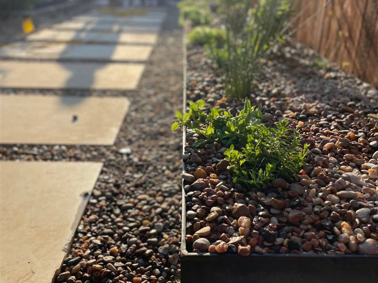 Steel planter and river rock hardscape in an Austin backyard